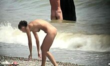 Une fille nue aux cheveux foncés se promène nue sur une plage