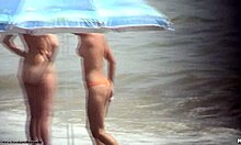 Seorang wanita telanjang berambut gelap berjalan telanjang di pantai